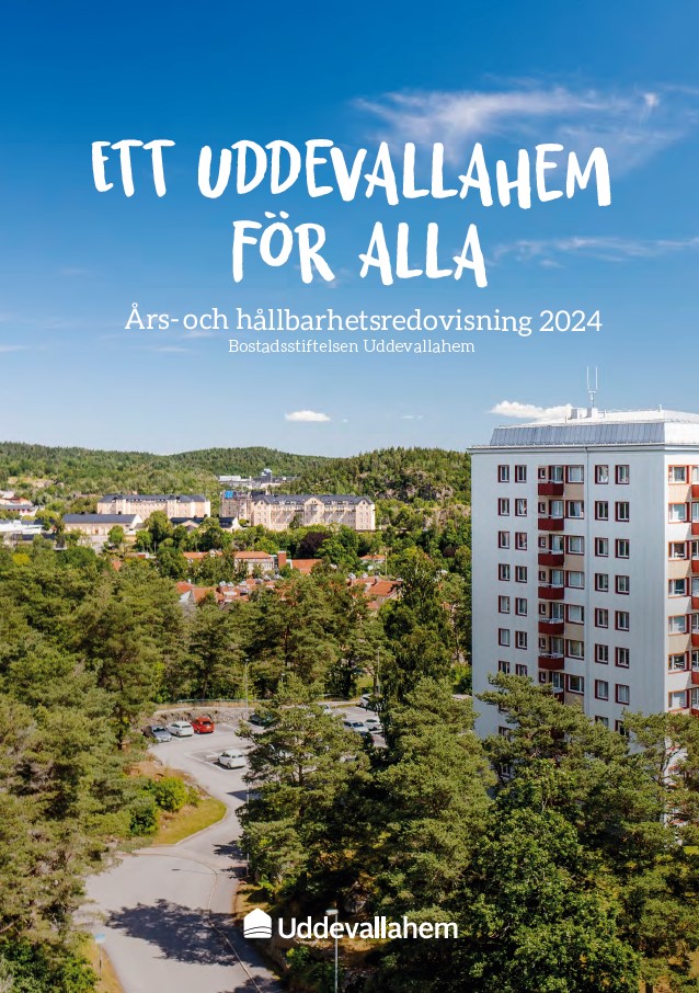 En väg som omsluts av träd och som leder fram till en parkering vid ett högt vitt flerbostadshus.