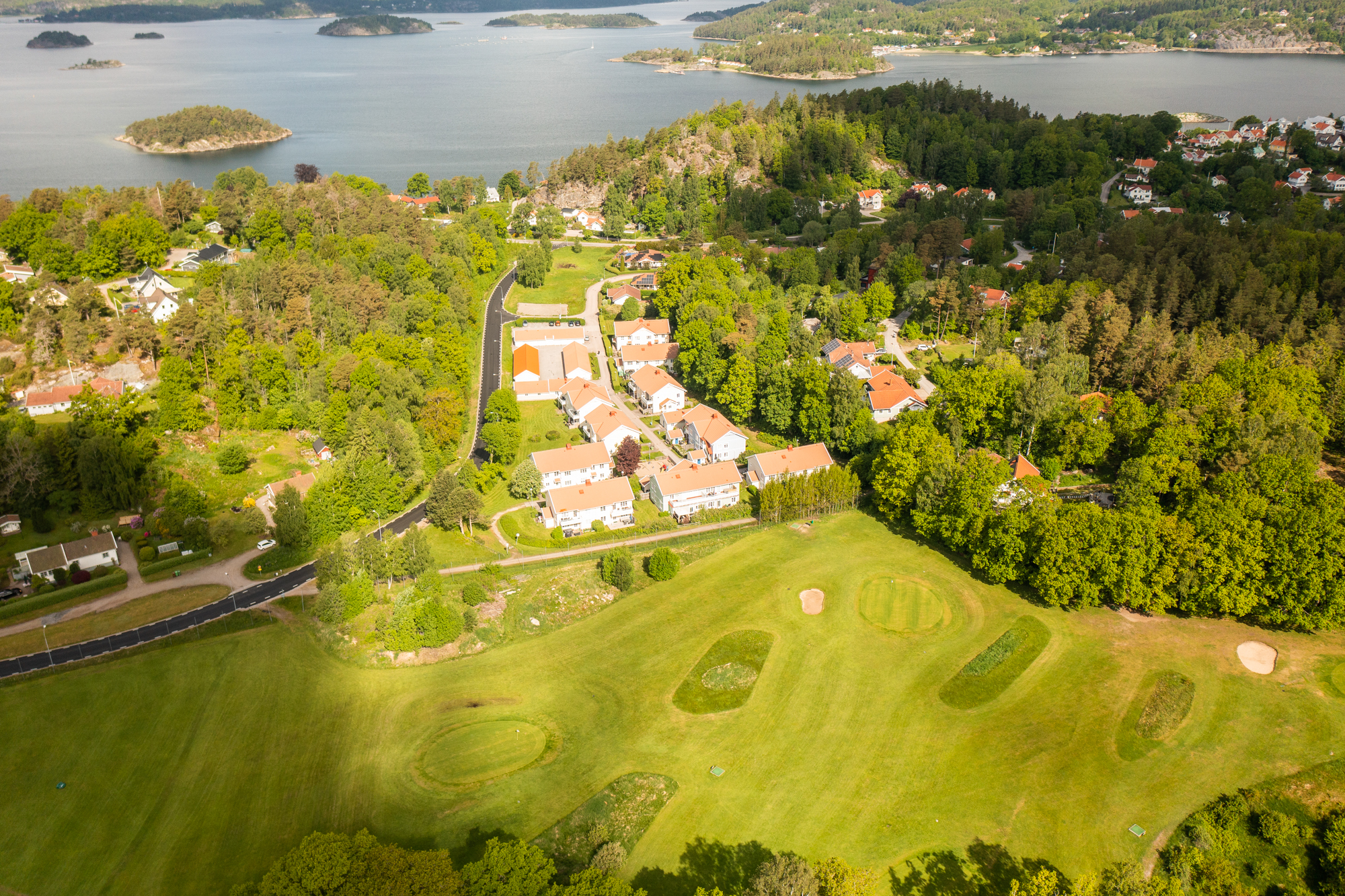 Flygbild på radhusen adress Korpemyrsvägen med golfbanan i förgrunden och havet i bakgrunden.